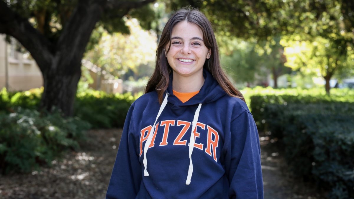 Pitzer student smiling surrounded by trees and greenery.