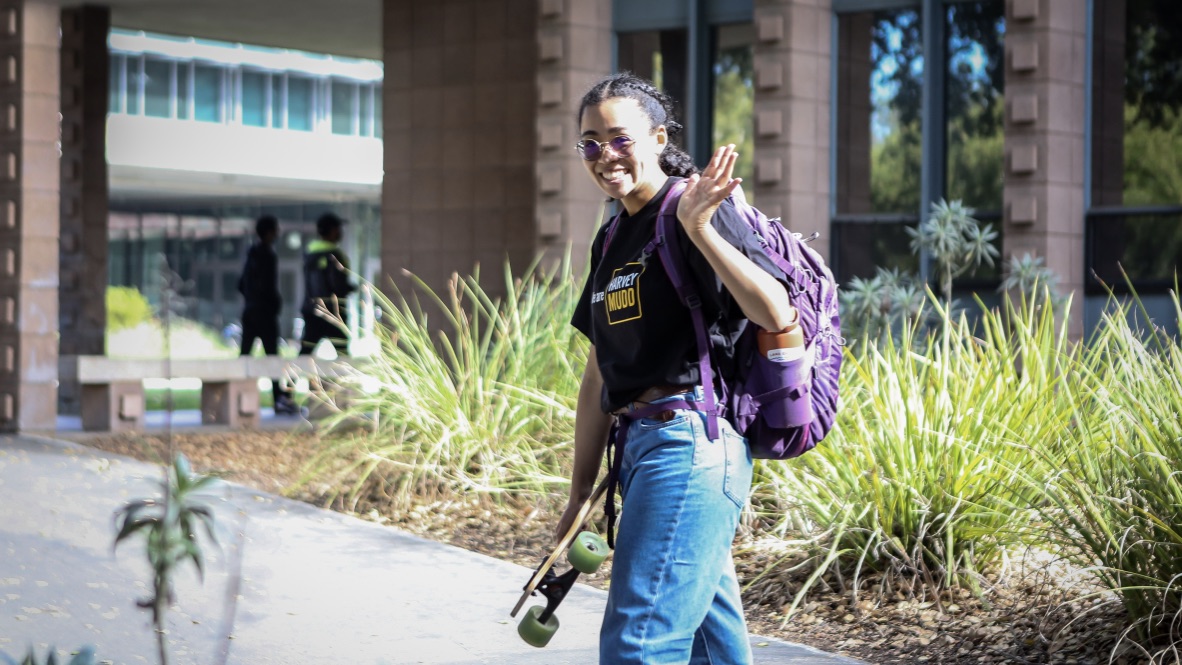 Harvey Mudd student waving and walking through campus.