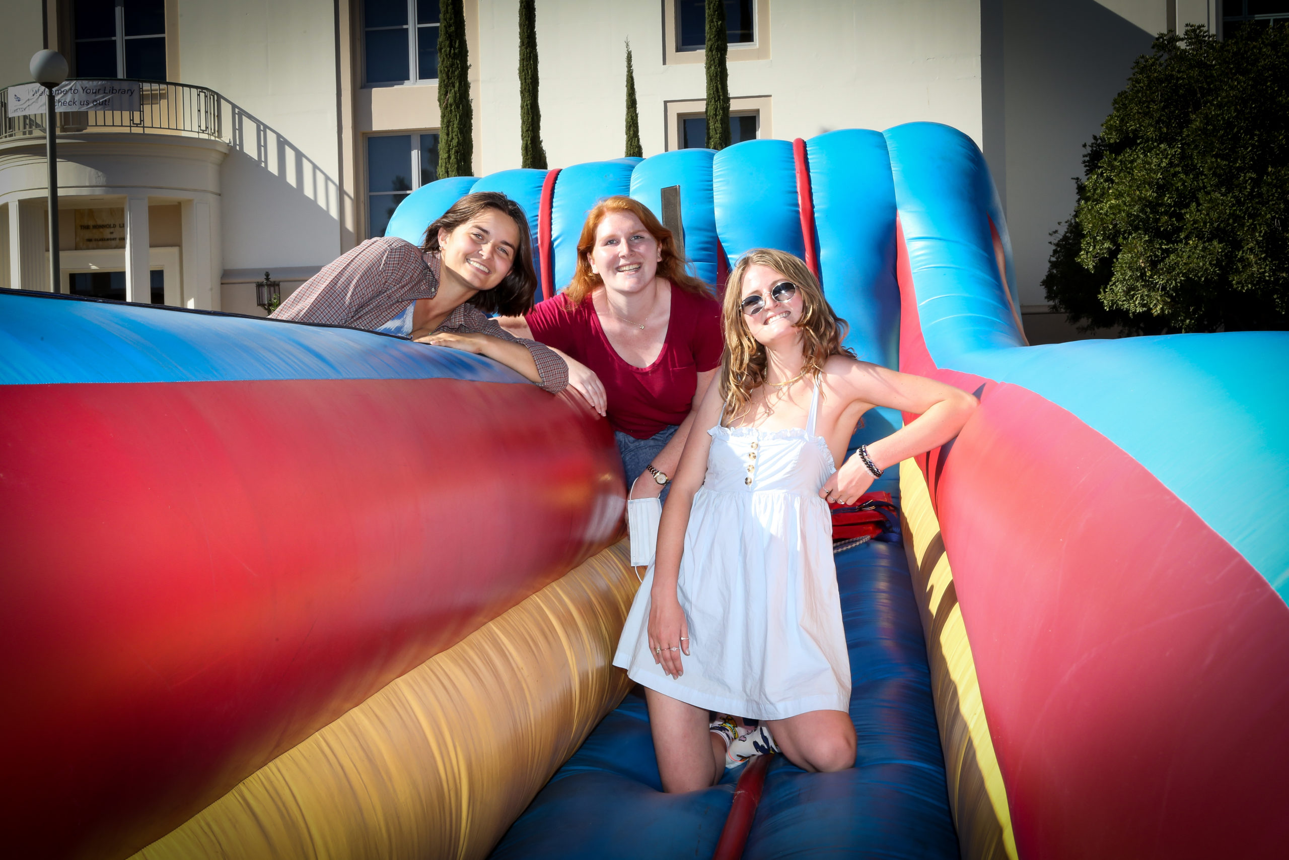 Three students leaning on bounce house