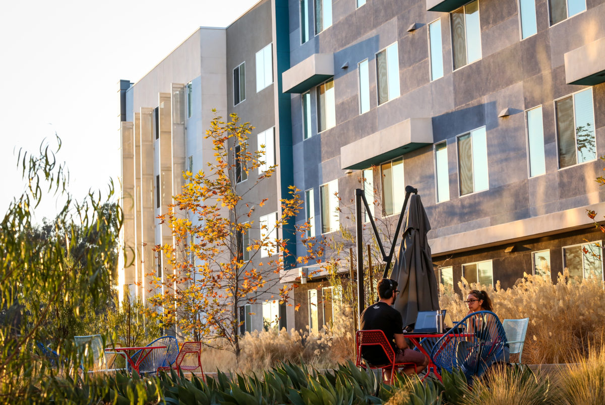 Students sitting at table outside KGI's Oasis housing building.