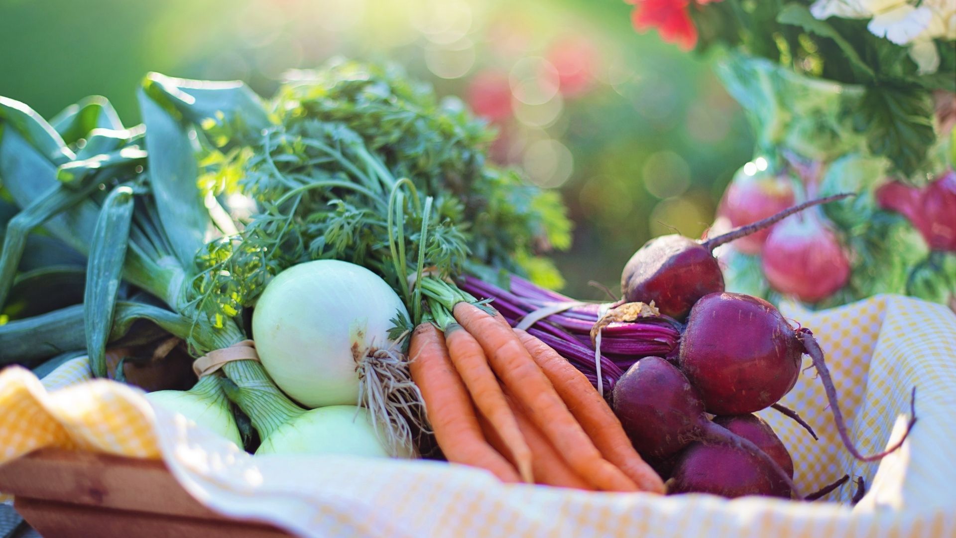 basket of fresh produce with carrots, beats, and onions